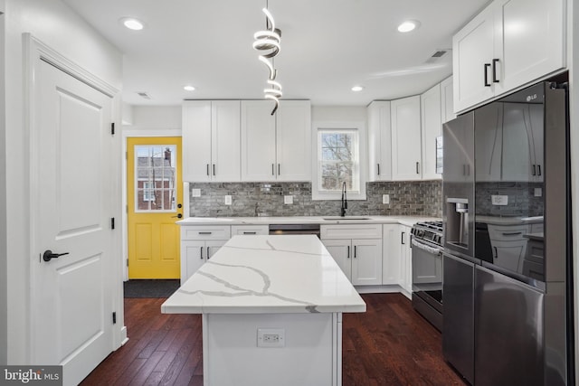 kitchen featuring sink, stainless steel appliances, a center island, light stone countertops, and white cabinets