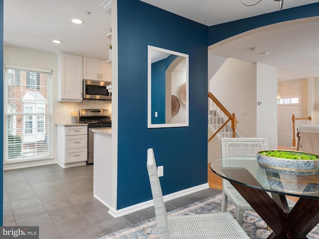 kitchen featuring white cabinetry, light tile patterned floors, tasteful backsplash, and stainless steel appliances