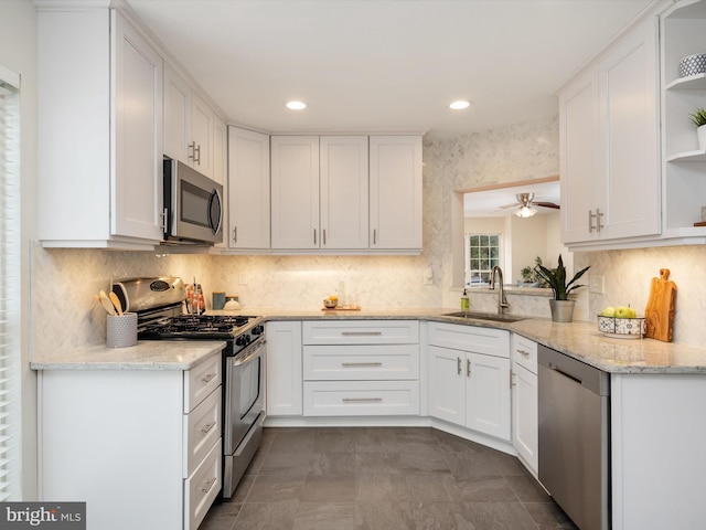 kitchen featuring stainless steel appliances, light stone countertops, sink, and white cabinets