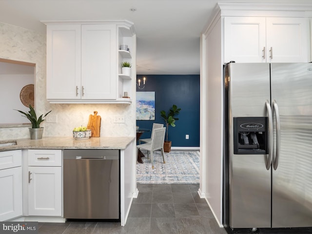 kitchen with light stone countertops, backsplash, stainless steel appliances, and white cabinets