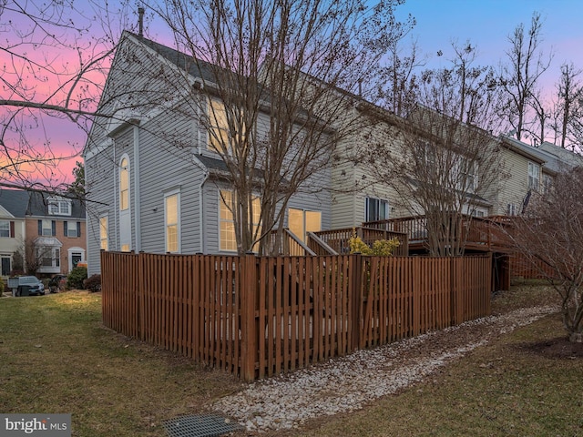 property exterior at dusk featuring a deck and a lawn