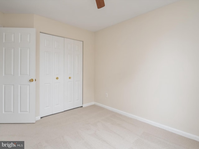 unfurnished bedroom with light carpet, a closet, and ceiling fan