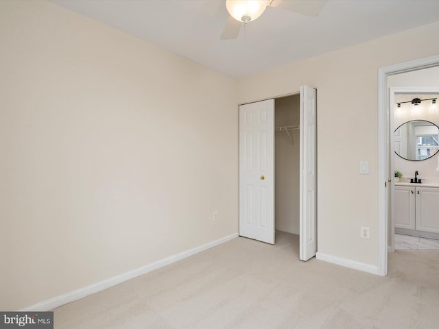 unfurnished bedroom with sink, light colored carpet, a closet, and ceiling fan