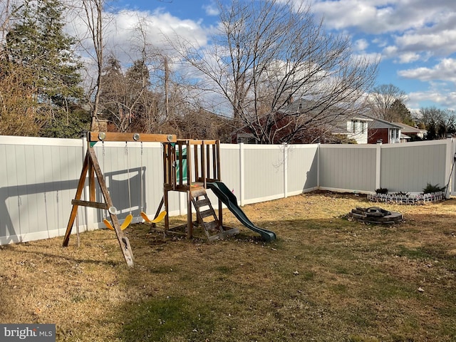 view of play area featuring an outdoor fire pit and a lawn