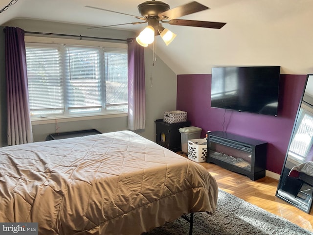 bedroom with ceiling fan, lofted ceiling, and light hardwood / wood-style floors