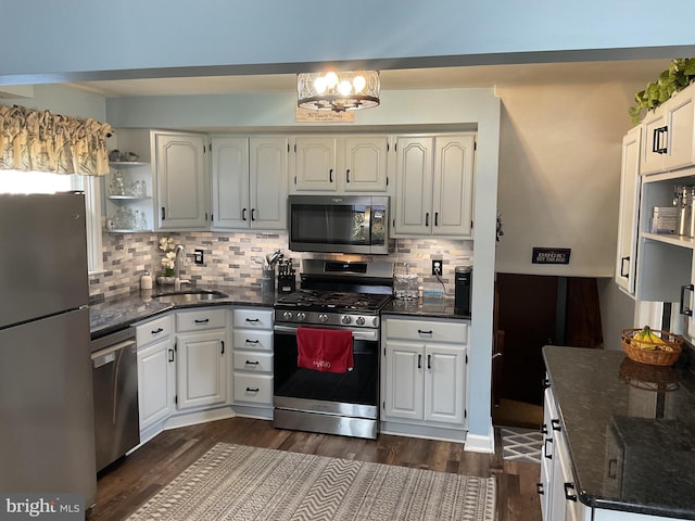 kitchen with white cabinetry, sink, stainless steel appliances, and dark stone countertops