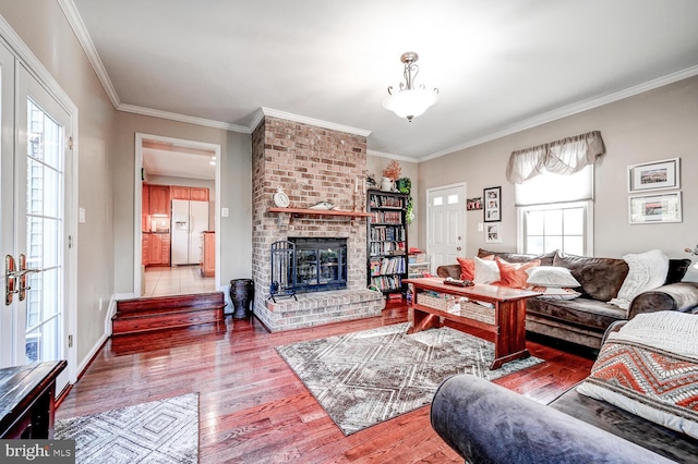 living room featuring ornamental molding, a brick fireplace, and hardwood / wood-style floors