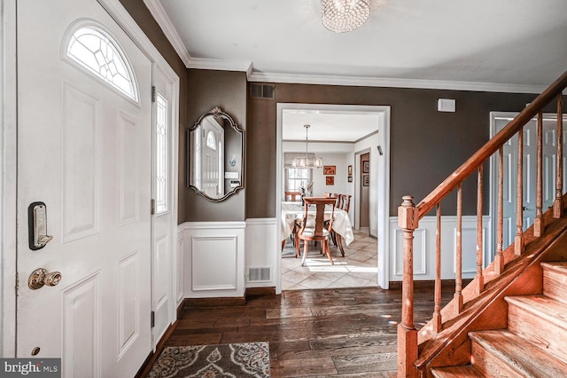 foyer entrance with an inviting chandelier, crown molding, and dark wood-type flooring