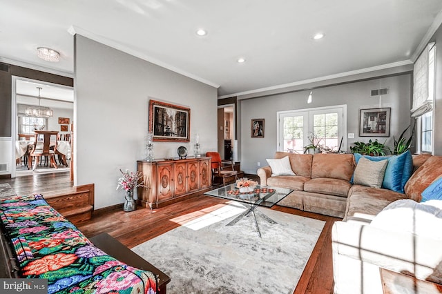 living room featuring a notable chandelier, crown molding, wood-type flooring, and french doors