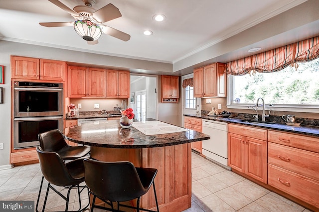 kitchen with a breakfast bar, sink, dark stone countertops, a center island, and white appliances