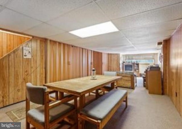 dining space featuring a paneled ceiling, wooden walls, and carpet floors