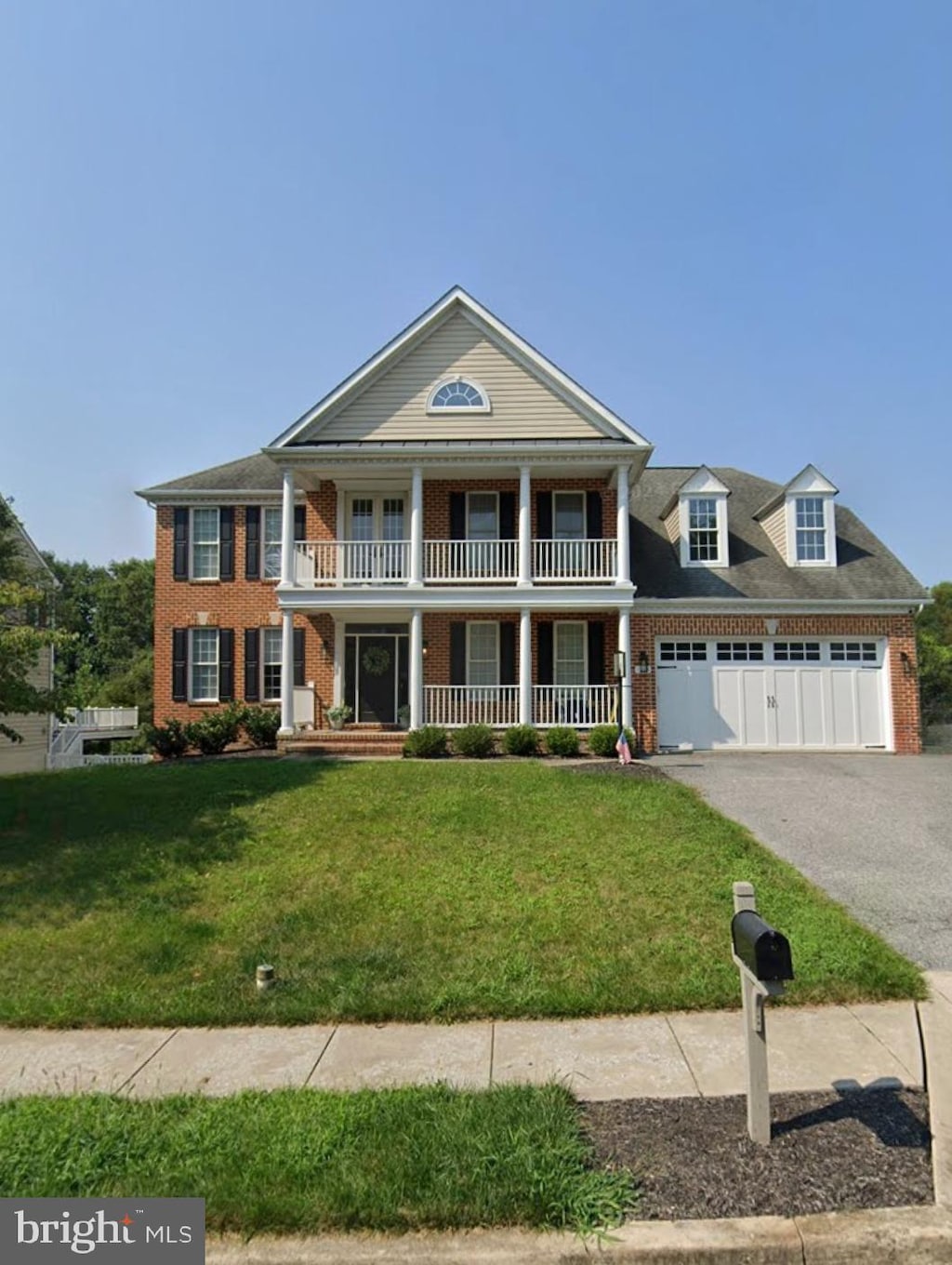 greek revival inspired property featuring a garage, covered porch, and a front yard