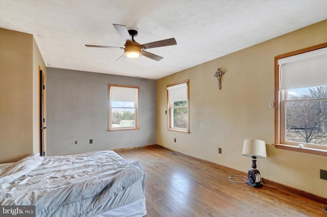 bedroom featuring ceiling fan, light hardwood / wood-style flooring, and a textured ceiling