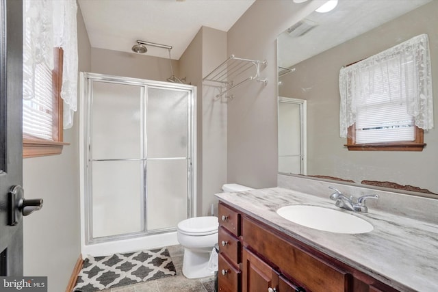 bathroom with vanity, a shower with door, and toilet