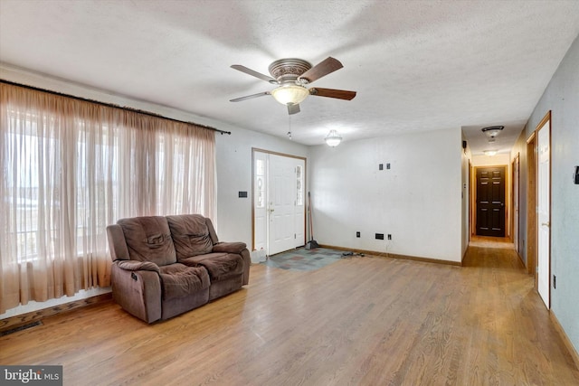 living room featuring ceiling fan, a textured ceiling, and light wood-type flooring