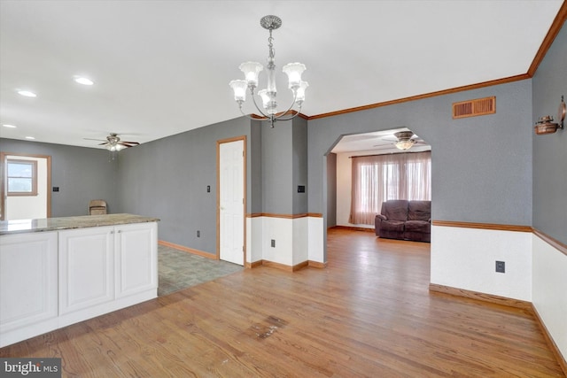 interior space featuring white cabinetry, ceiling fan with notable chandelier, light wood-type flooring, and decorative light fixtures