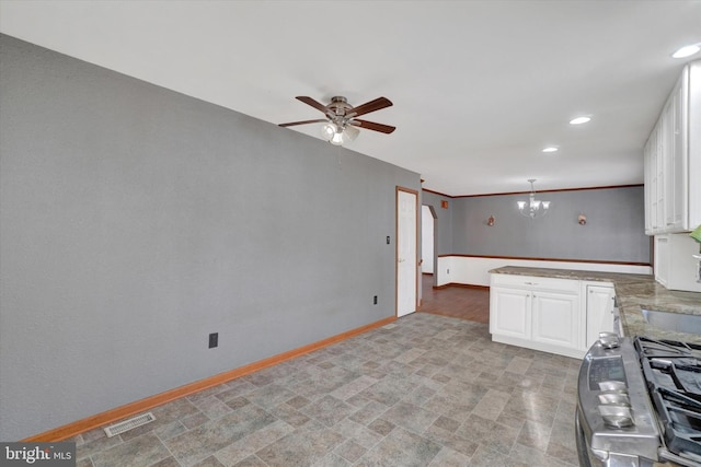 kitchen with ceiling fan with notable chandelier, pendant lighting, white cabinetry, stainless steel gas range oven, and crown molding