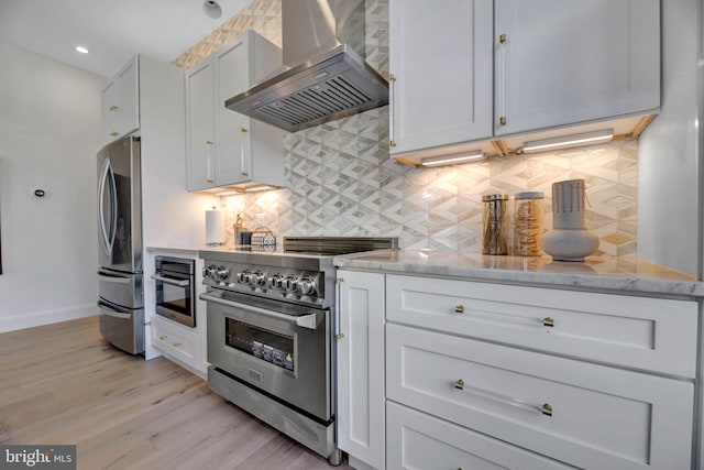 kitchen with white cabinetry, light stone countertops, island range hood, and stainless steel appliances