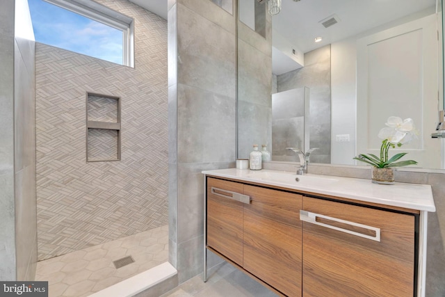 bathroom with vanity and a tile shower