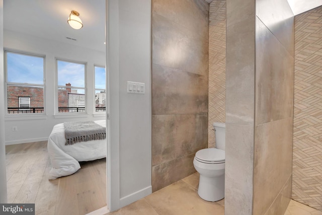 bathroom with hardwood / wood-style flooring, toilet, and tile walls