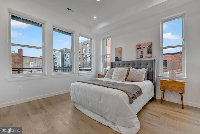 bedroom with light hardwood / wood-style floors and multiple windows