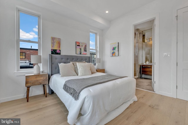 bedroom with multiple windows, light hardwood / wood-style floors, and ensuite bath