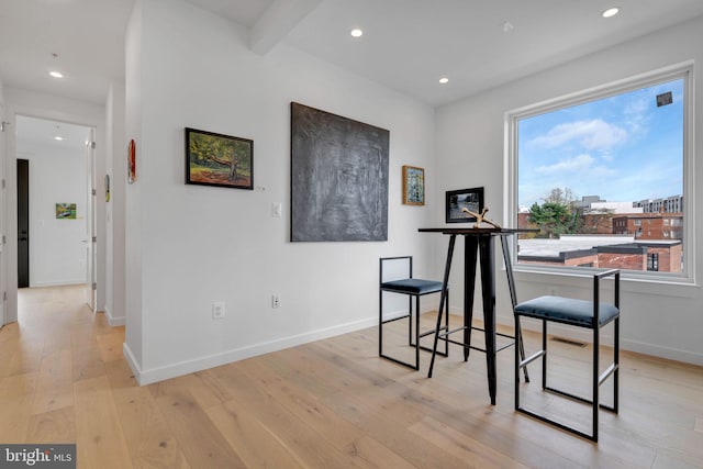 dining area with beam ceiling and light hardwood / wood-style floors