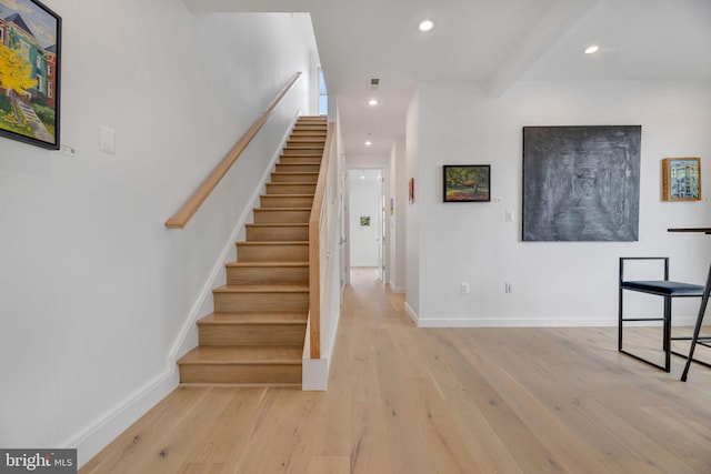 staircase with wood-type flooring and beamed ceiling