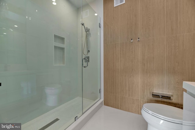 bathroom with walk in shower, toilet, tile patterned flooring, and tile walls