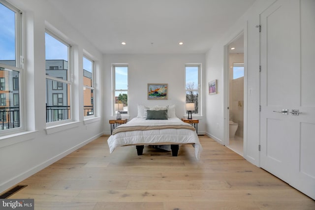 bedroom with connected bathroom and light hardwood / wood-style flooring