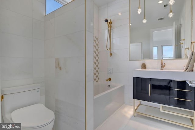 full bathroom with tile walls, vanity, tiled shower / bath combo, and toilet