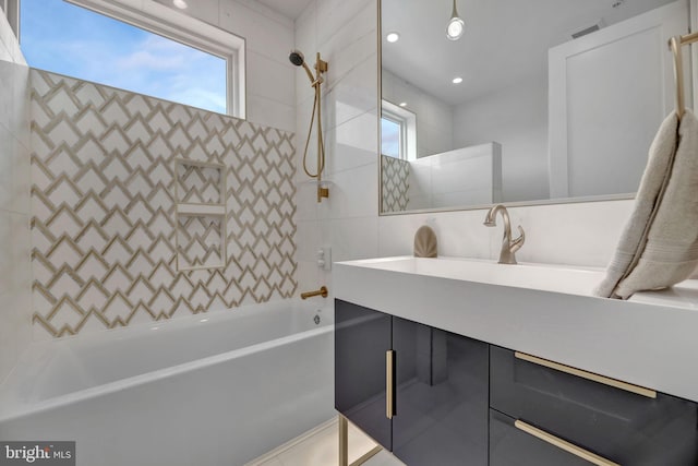 bathroom featuring vanity, tiled shower / bath, tile walls, and a healthy amount of sunlight