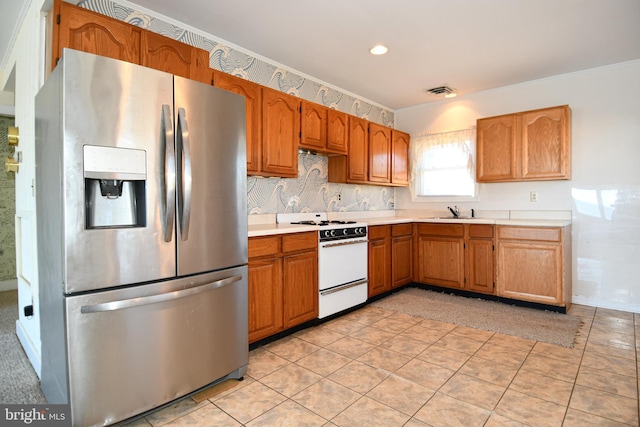 kitchen with white stove, sink, light tile patterned flooring, and stainless steel refrigerator with ice dispenser