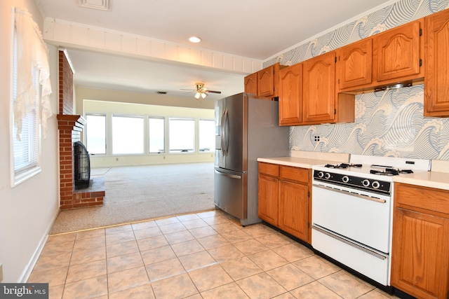 kitchen with a fireplace, white gas range, ceiling fan, stainless steel refrigerator with ice dispenser, and light carpet