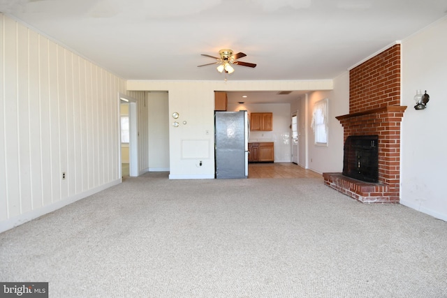 unfurnished living room with ceiling fan, light colored carpet, and a brick fireplace