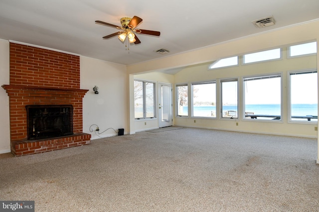 unfurnished living room featuring a water view, carpet floors, ceiling fan, and a brick fireplace