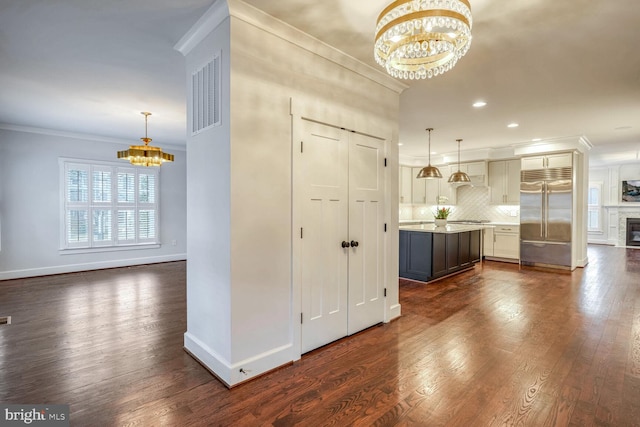 kitchen featuring built in refrigerator, crown molding, pendant lighting, and a notable chandelier