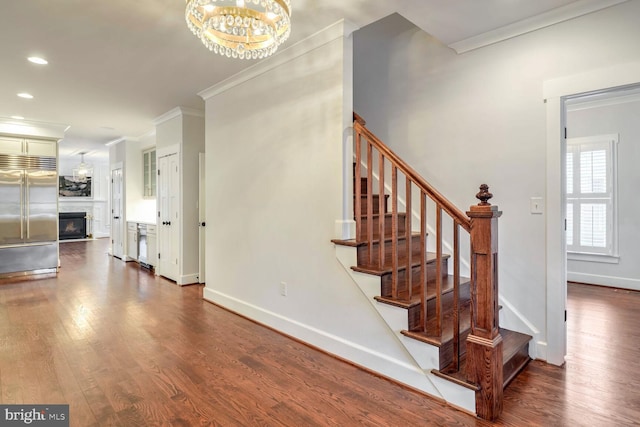 stairs featuring an inviting chandelier, hardwood / wood-style floors, and crown molding