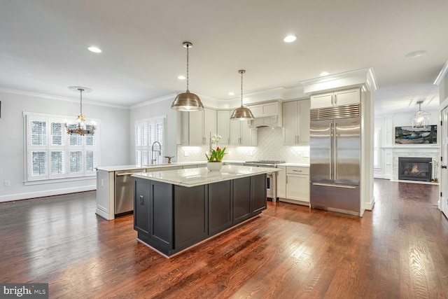 kitchen with sink, high end appliances, crown molding, pendant lighting, and light stone countertops