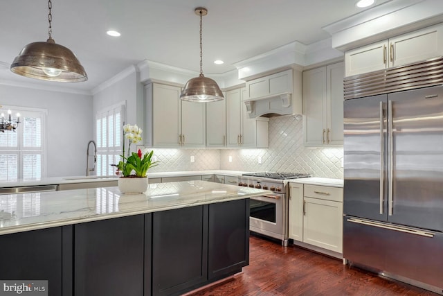 kitchen with high end appliances, sink, pendant lighting, and light stone counters