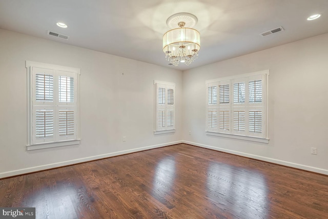 empty room featuring an inviting chandelier and dark hardwood / wood-style flooring