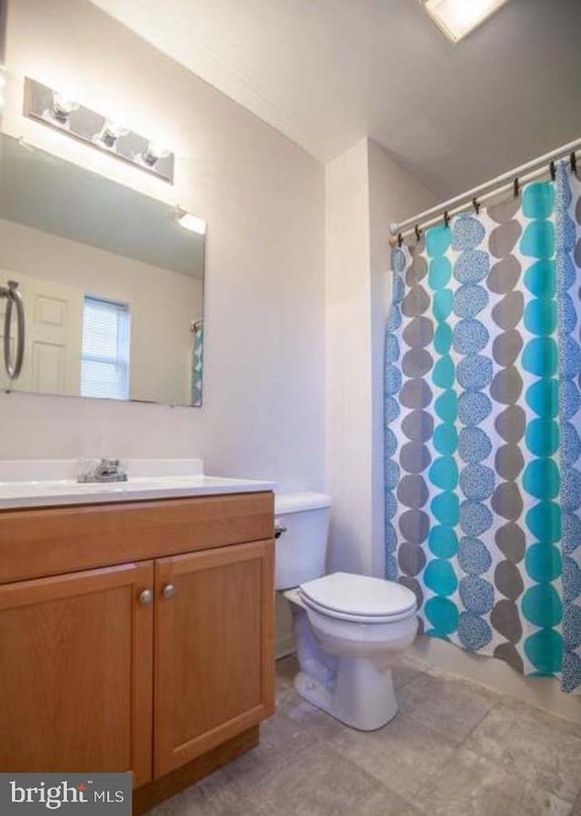 bathroom with walk in shower, vanity, and toilet