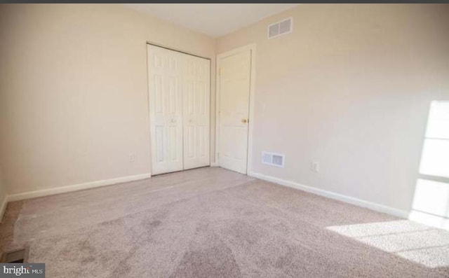 unfurnished bedroom featuring a closet and light carpet