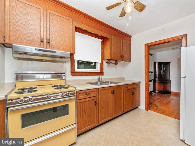 kitchen featuring gas range, white fridge, sink, and ceiling fan