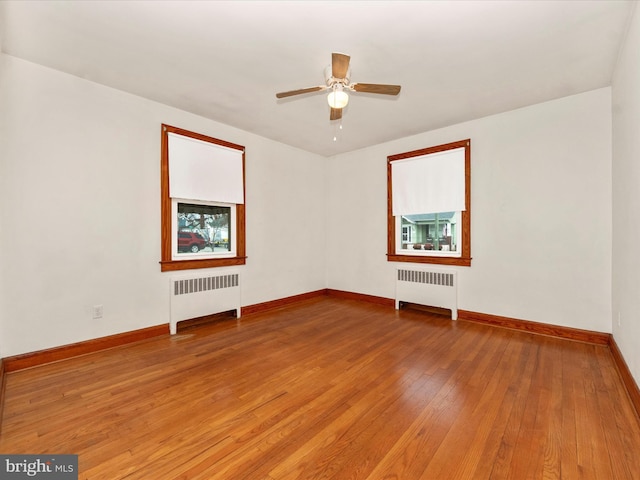 spare room featuring radiator, hardwood / wood-style floors, and ceiling fan