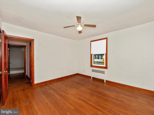 unfurnished room with ceiling fan, radiator heating unit, and hardwood / wood-style floors