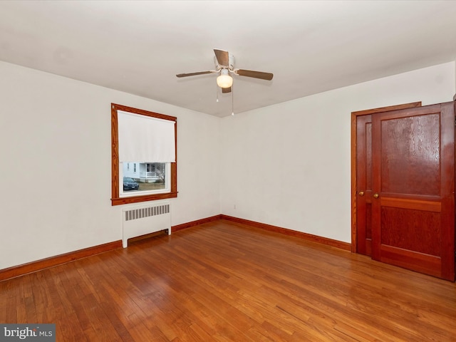 spare room featuring hardwood / wood-style flooring, radiator, and ceiling fan