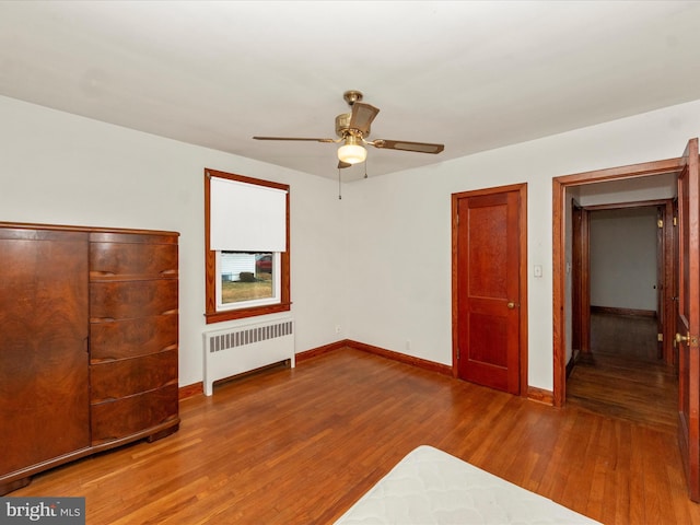 unfurnished bedroom with ceiling fan, radiator heating unit, and hardwood / wood-style floors