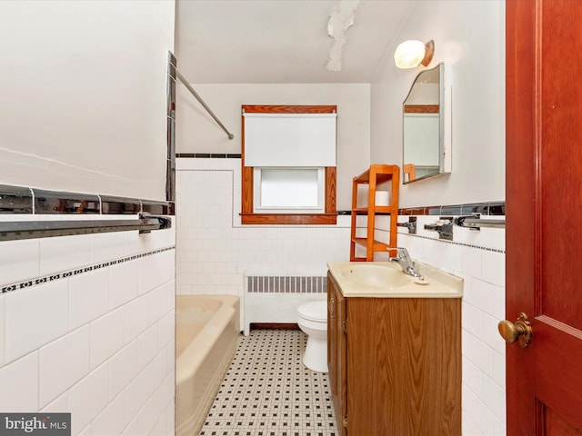 bathroom with toilet, tile walls, vanity, radiator, and a bathing tub