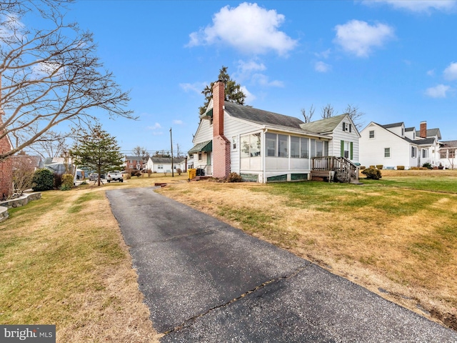 view of property exterior featuring a sunroom and a yard